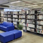 Fotografia da Biblioteca da Unijorge com poltronas, puffs e estantes com livros